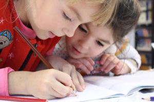 Deux enfants entrain d'écrire sur un cahier